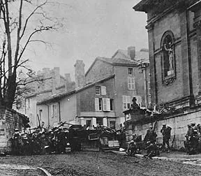 American soldiers gathered at a barricade in a village street beside a stone church, in black and white