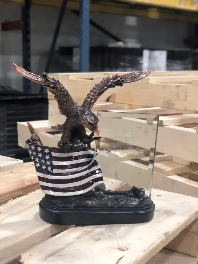 Bronze eagle trophy with a painted American flag and an etched glass LockLeed Employer of The Year plaque, on wooden pallets in a warehouse