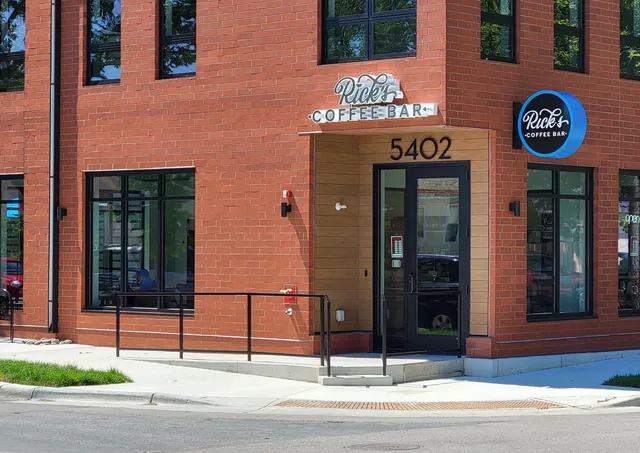 Corner entrance of a red brick building with Rick's Coffee Bar signs above the door