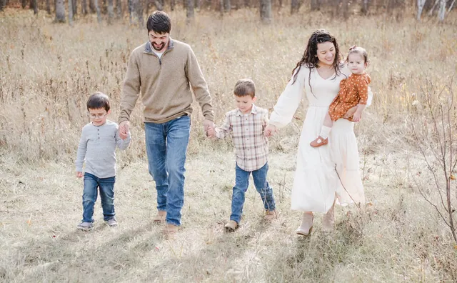 Brandon Sullivan, his wife Valeria and their three children walk hand in hand through a field of tall dry grass