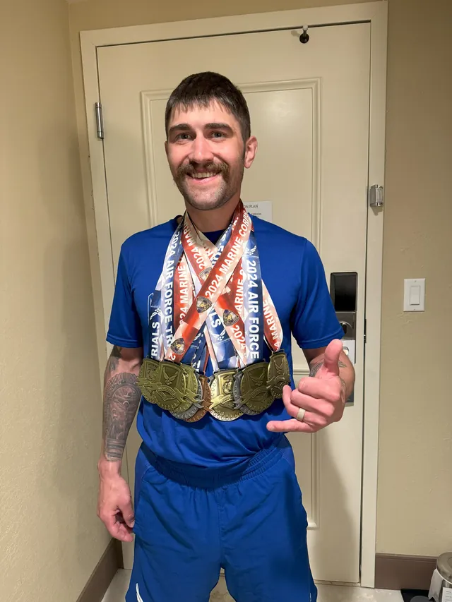Brandon Sullivan, in a blue Air Force shirt, gives a thumbs-up while wearing his stack of medals from the trials in Las Vegas