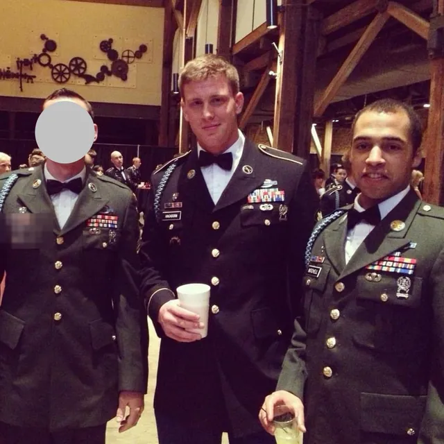 John Mitchell in Army dress uniform and bow tie at a formal event with two fellow soldiers, one with his face covered