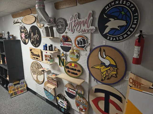 Shop wall of laser-cut wooden signs, including Minnesota Timberwolves, Vikings and Twins logos and personalized name plaques