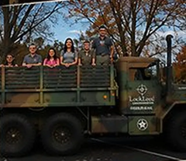 LockLeed team members standing in the bed of an Army cargo truck with a LockLeed logo on its door